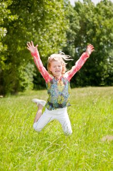 Child of 5 years old jumping high in the field arms outstretched