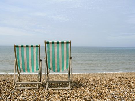 two empty deck chairs facing the sea