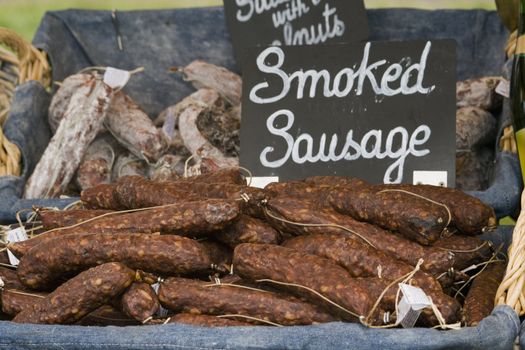 a basket of smoked sausages for sale on a market stall