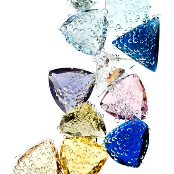 Multi-colored gems falling into water isolated on white.