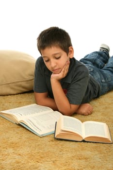 Boy in a room reading a book over a carpet. 