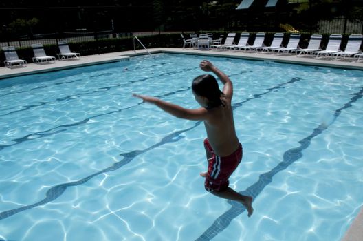 Little boy jumping into pool