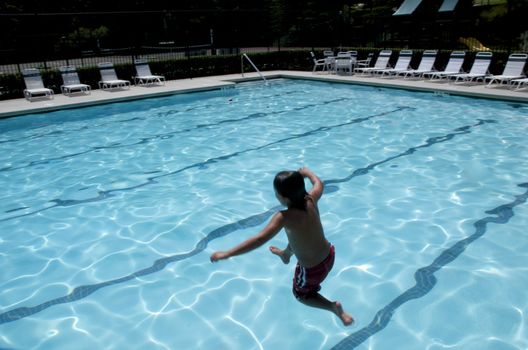 Little boy jumping into pool