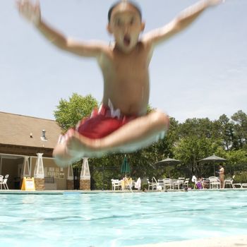 Little boy jumping into pool