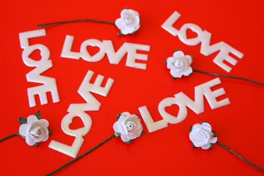 The word love on a red background with small white roses