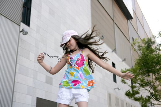 Brunette teen little girl dancing mp3 headphones music in the city
