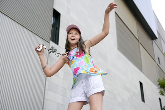 Brunette teen little girl dancing mp3 headphones music in the city