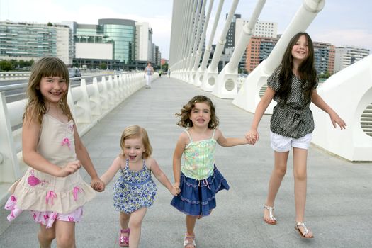 Four little girl group walking in the city bridge downtown buildings