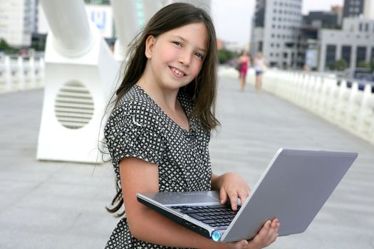 Beautiful little girl with laptop computer downtown city bridge