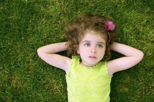 Beautiful little toddler girl happy lying on the green grass