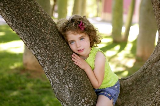 Beautiful blue eyes little girl and a tree on the park green grass