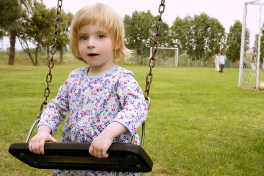 Beautiful toddler blond girl playing on the park playground