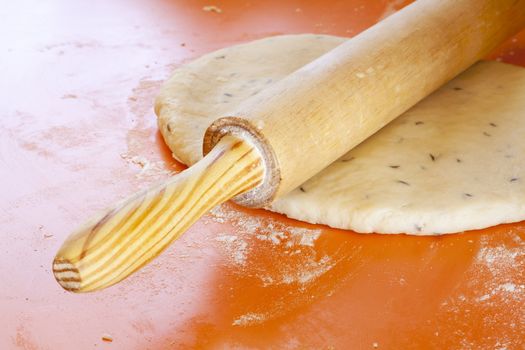 Wooden rolling pin on rolled dough with spices