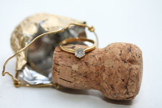 A solitair yellow golden engagement ring on a champagne cork, celebrating a new engagement