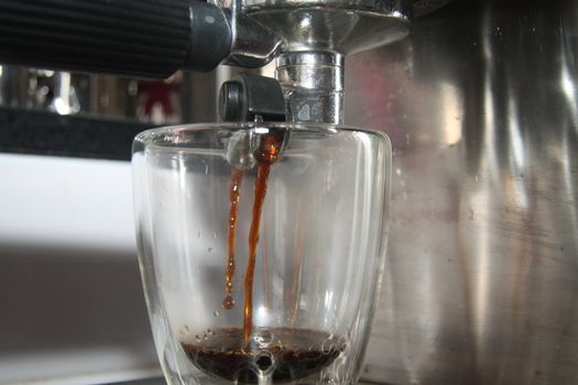 A glass in close up under a traditional italian espresso maker
