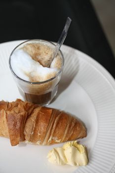 A typical French breakfast: a croissant with butter and an espresso coffee with milk