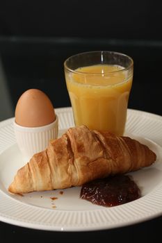 A French breakfast: a croissant with marmelade, orange juice and an egg