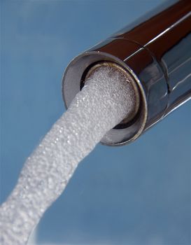 bubbling, flowing water from the tap isolated on blue