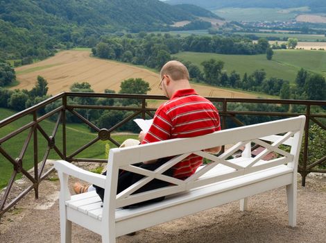 One man enjoy a book outdoors on a warm summer's day.