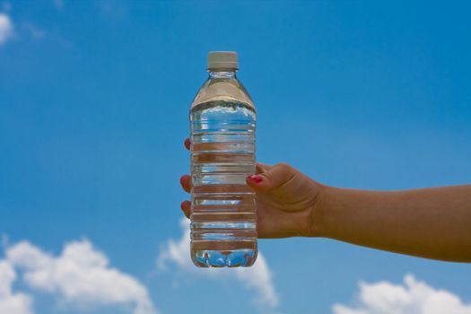 teen girl holding a water bottle up with a blue cloudy sky