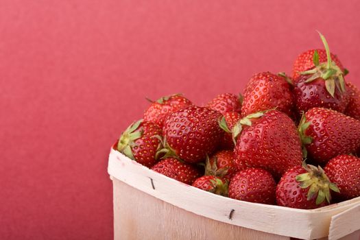wooden quart of ripe strawberries on a solid background