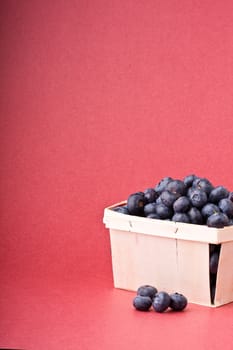 wooden quart of blueberries on a red background