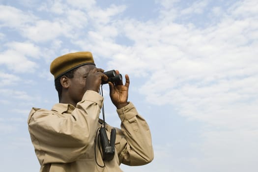 An african policemen is watching through bincolurars. 
Location: Southern Ethiopia, near Omo river