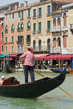 A gondoliere at the Grand Canal in Venice, Italy. Gondolas are the typical boats in Venice and a tour in such a boat is a highlight of an touristic visit.