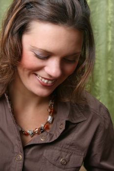 Beautiful brunette female wearing a brown shirt against a green background