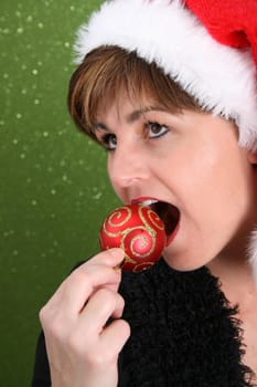 Adult female wearing a christmas hat, attempting to bite a decoration
