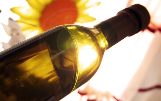 The sun is shining behind a bottle of wine
