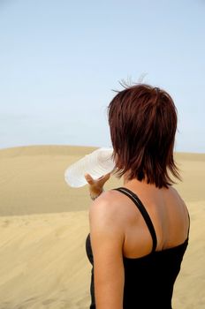 Woman is drinking water in the desert.