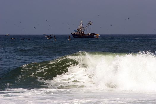 Trawler with surf wave in the foreground, Arica harbor, Chile, Pacific Ocean