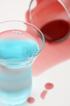 Spilt red wine and a blue drink and a shot glass