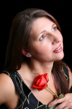 Brunette model holding a red rose, looking into the distance