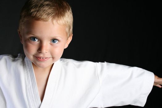 Young boy wearing his karate uniform on a black background

