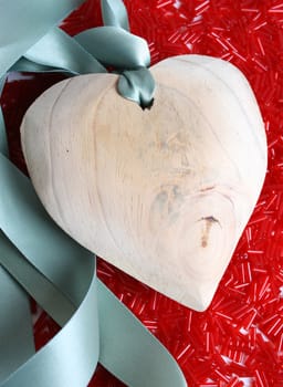 Large wooden heart on a bed of red beads