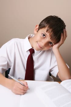 Teenage School boy busy with his homework, wearing uniform
