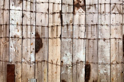Wooden fence entangled by a barbed wire background