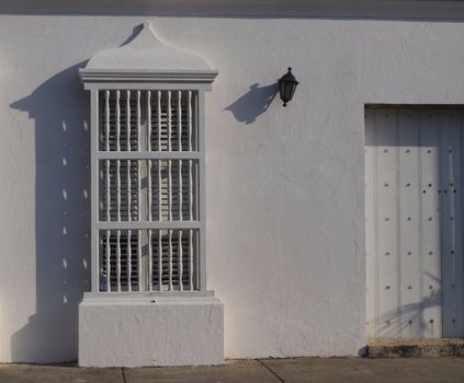 Architectural details on white colonial wall: window, lamp, door