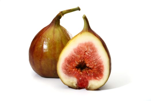 Two delicious figs, one sliced in half over a white background