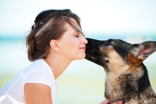 Dog is licking a face of a young beautiful woman