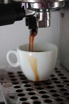 Espresso cup under a traditional Italian espresso machine