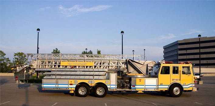 This is a side view of a fire truck with ladders and a bucket used for reaching fires in high places.