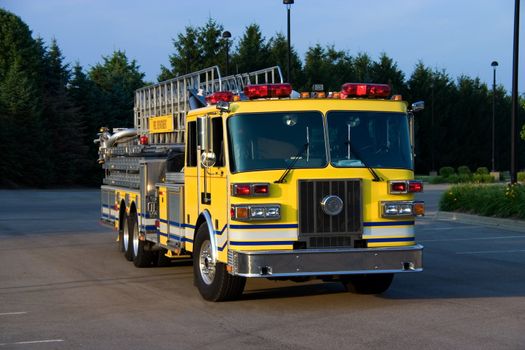 This is a picture of the front of a yellow fire truck used for reaching fires in high places, such as, tall office buildings.