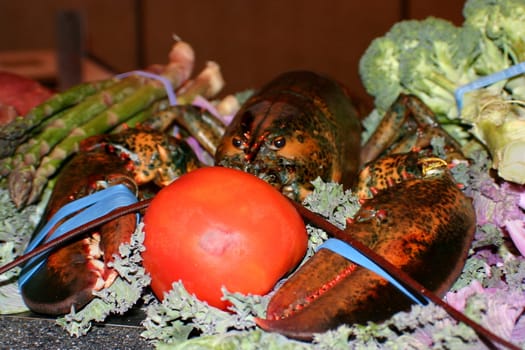 This is a live lobster on a tray with vegetables, ready for a pot of boiling water.