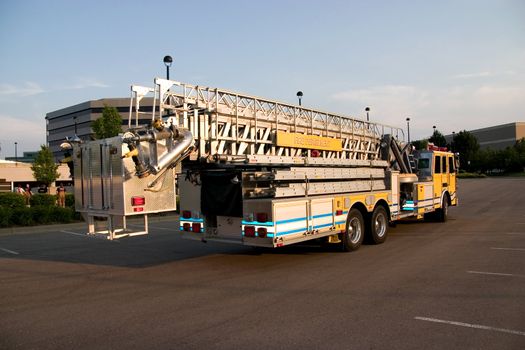 This is the rear view of a fire truck with ladders and a bucket used for reaching fires in high places.