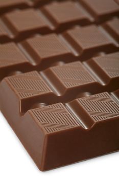 A macro photo of a large bar of milk chocolate. Shallow depth of field, focusing on the top of the first row.