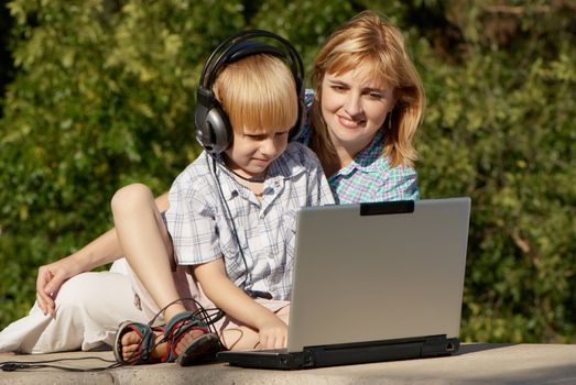 The little boy and mother with the laptop in park