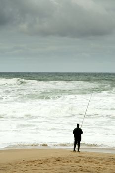 Man fising nearby stormy beacj